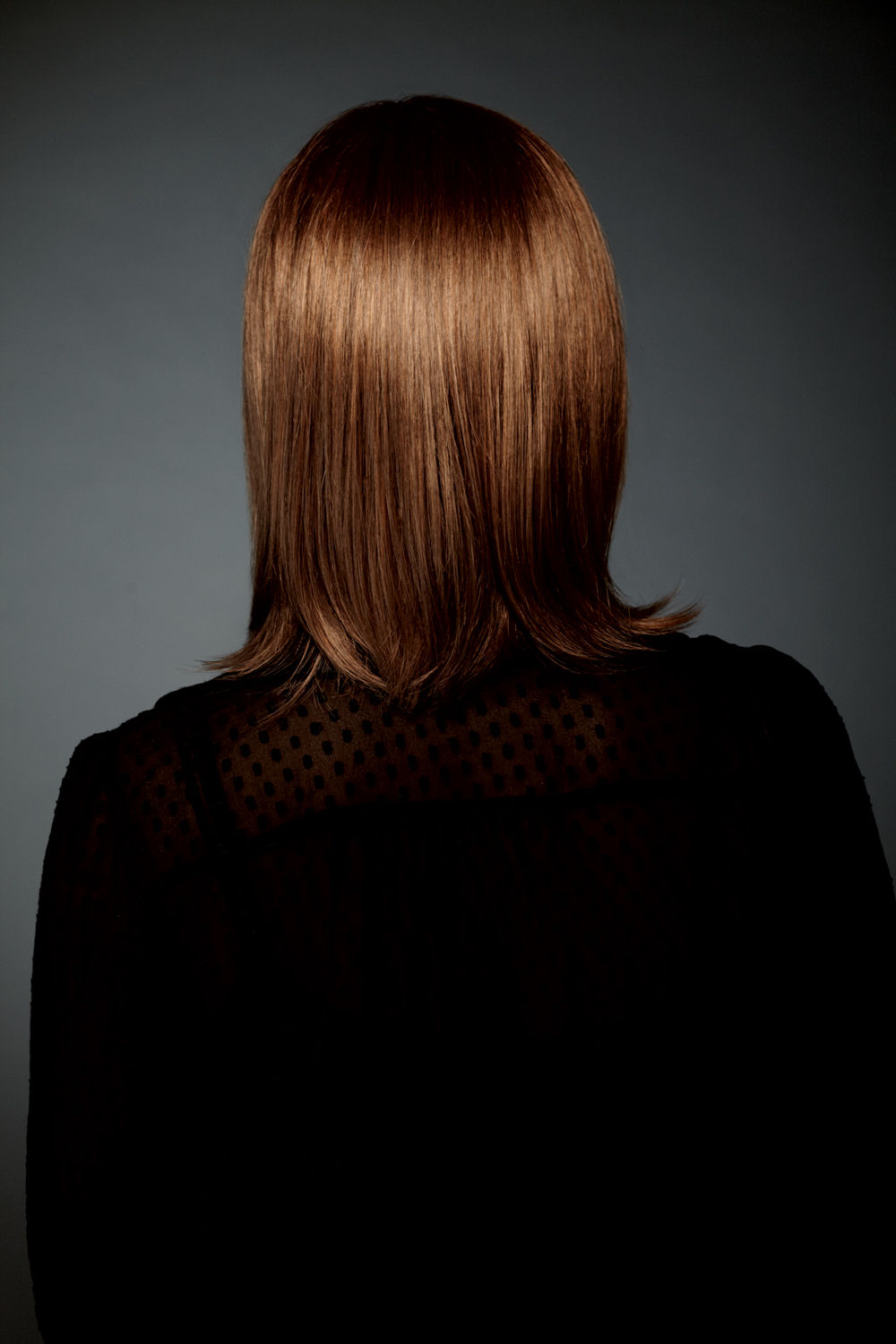 Back of a lady wearing shoulder length wig with fringe